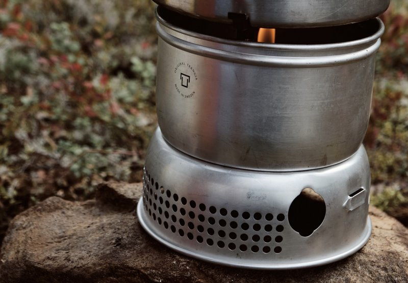 Sturm-Gaskocher mit Spiritus von Trangia Spiritus-Gaskocher von Trangia steht auf Felsen und erhitzt einen Topf.