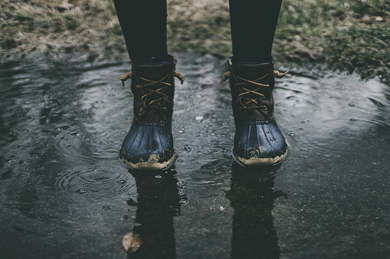 Person steht bei Regen in einer Pfütze